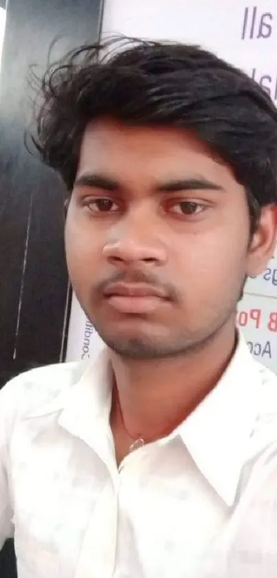 Portrait of a young man in a casual white shirt, posing thoughtfully.