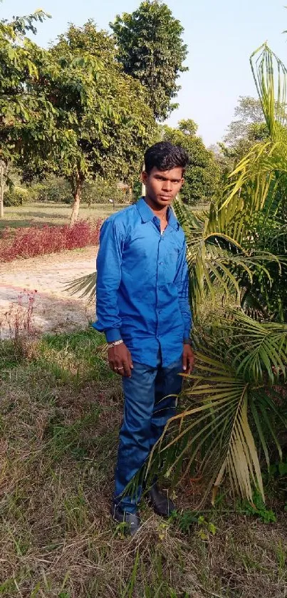 A person in blue attire surrounded by lush greenery in a serene outdoor setting.