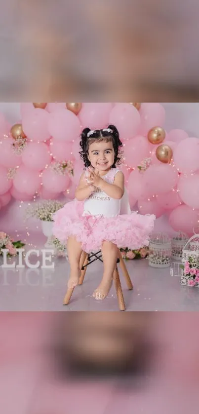 Smiling toddler with pink balloons and princess dress in festive setting.