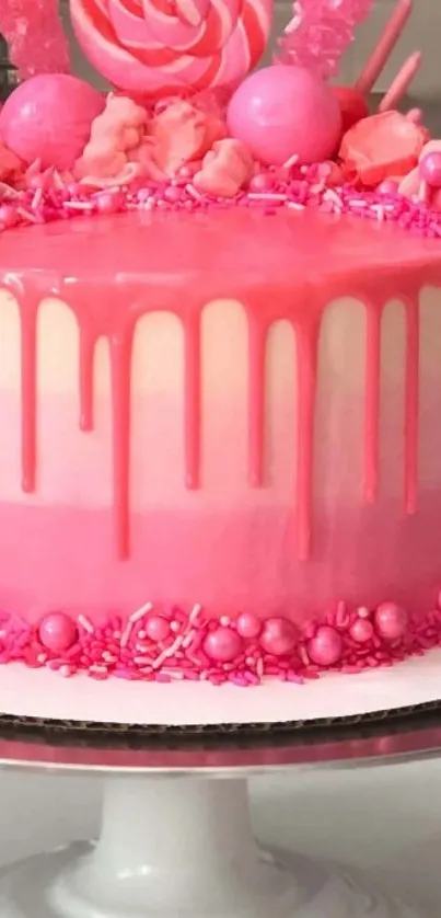 Pink candy-themed cake with decorative toppings on a stand.