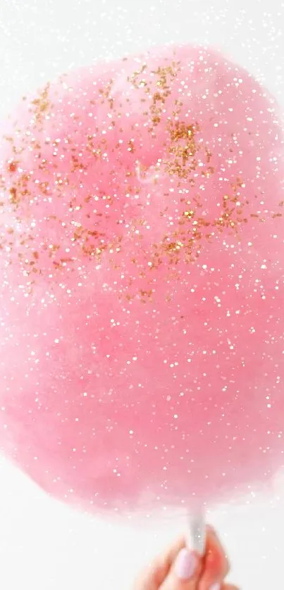 Pink cotton candy with golden sprinkles, handheld.