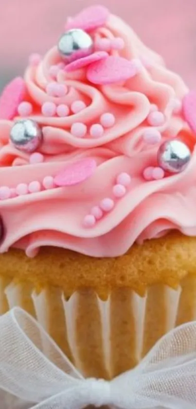 Pink cupcake with frosting and decorative pearls.