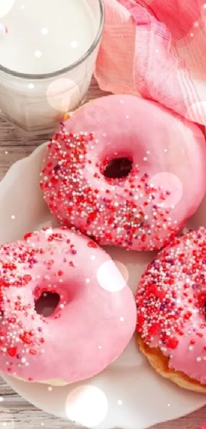 Pink donuts with sprinkles and a glass of milk on a wooden table.