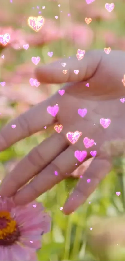 Hand touching pink flower with floating hearts in nature scene.