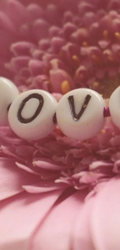 Pink daisy flower with 'LOVE' beads on petals.