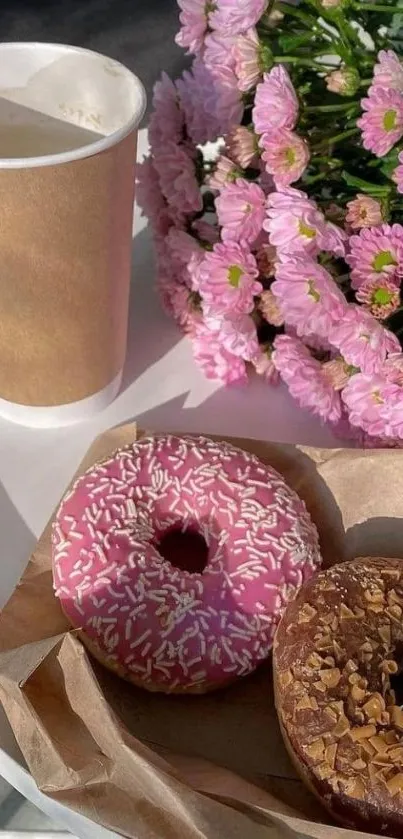 Donuts and pink flowers with coffee on a table.