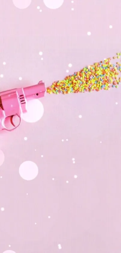 Pink gun shooting colorful candy on a pink background.