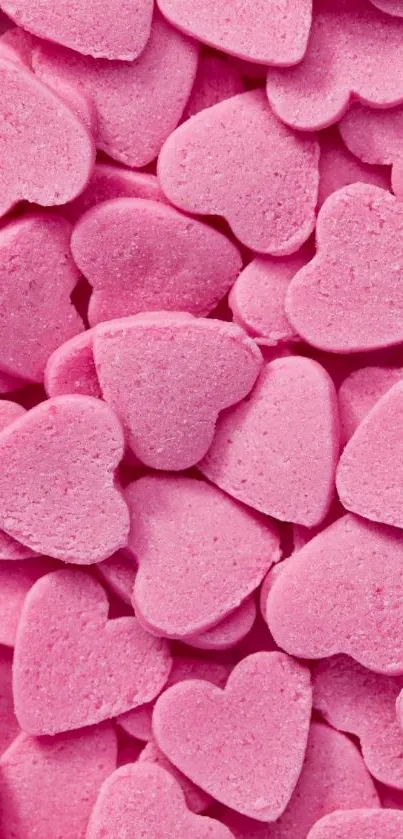 A colorful wallpaper featuring pink heart-shaped candies piled together for mobile devices.