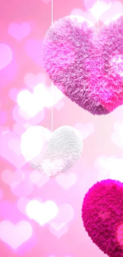 Three fuzzy hearts hanging against a pink background.