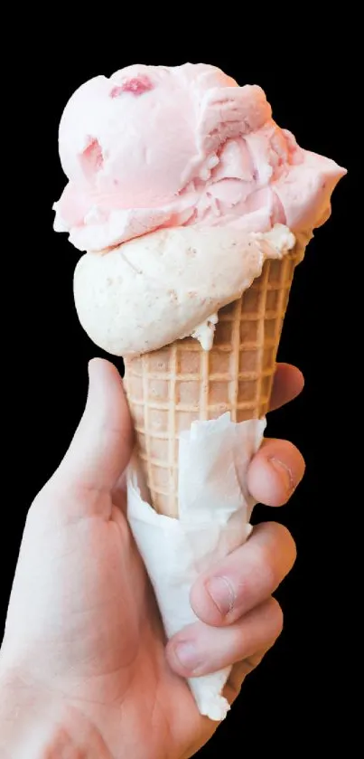 Hand holding pink ice cream cone against white background.