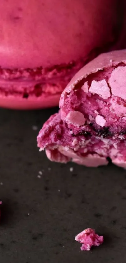 Close-up of pink macarons on a dark background.