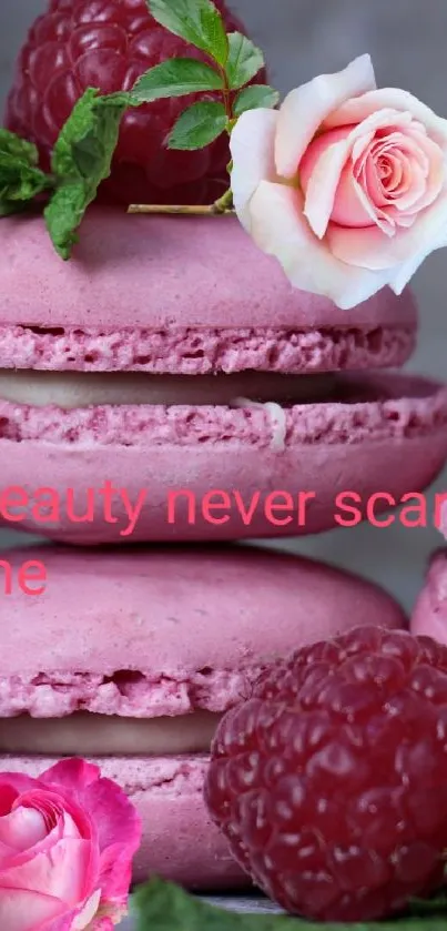 Pink macarons with raspberries and roses against gray background.