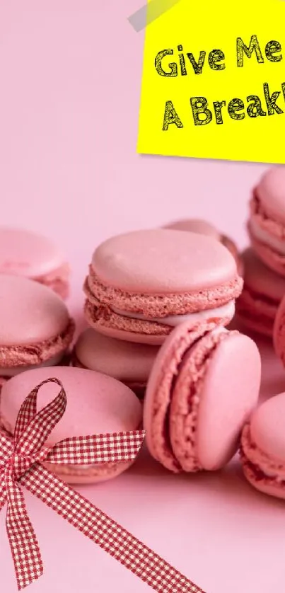 Pink macarons with a 'Give Me a Break' note on a wallpaper.