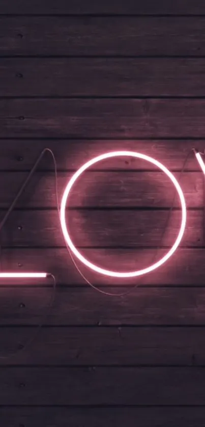 Pink neon 'LOVE' sign on dark wooden background.