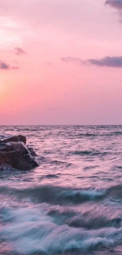 Pink ocean sunset with waves and rocks, ideal for mobile wallpaper.