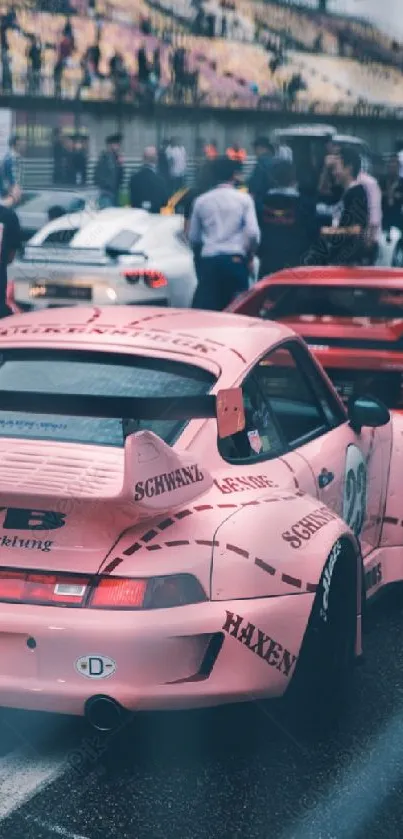 Pink racing car on a busy circuit track with spectators.