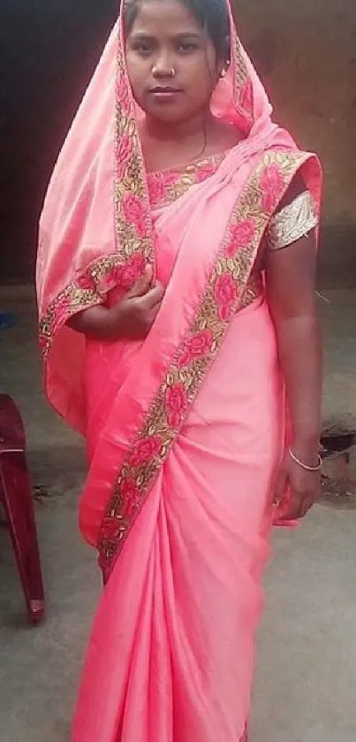 Woman in a bright pink sari standing outdoors.