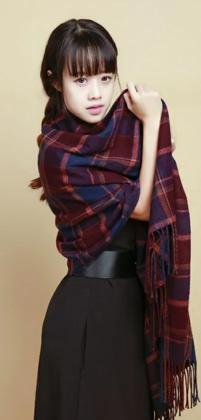 Woman wearing a plaid scarf with neutral beige background.