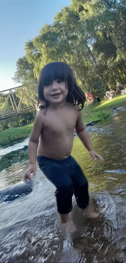 Child plays by a river under a green canopy.