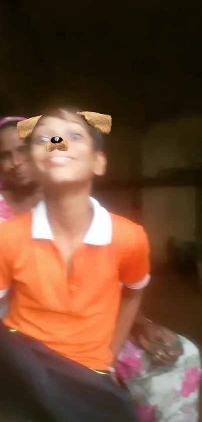 Child in orange shirt with playful dog filter, smiling in a home setting.