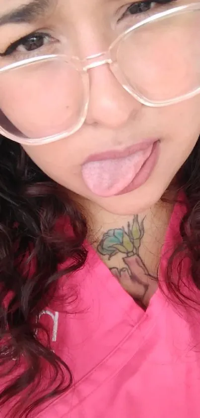 Woman wearing glasses with playful expression in a pink top.