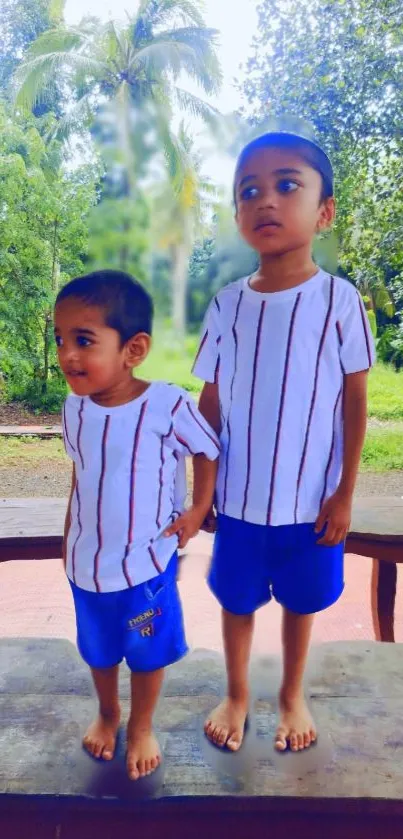 Children playing outdoors in lush greenery with matching outfits.