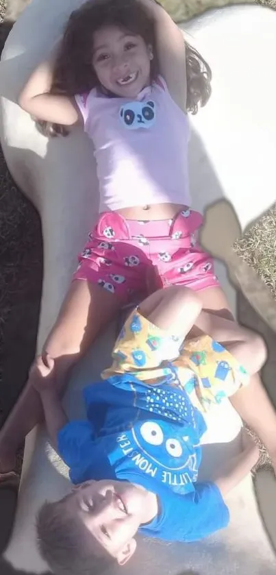 Two smiling kids playing outdoors, enjoying the sunny day.