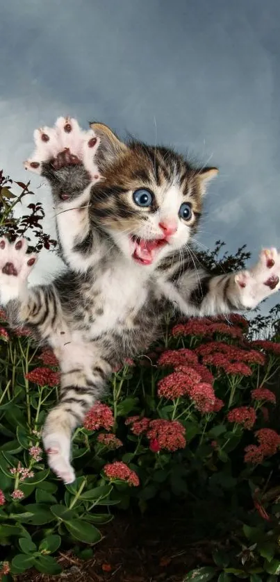 Playful kitten jumping in a colorful garden with blue sky backdrop.