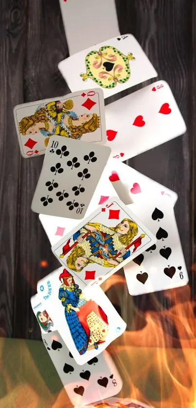 Playing cards falling in flames on dark wood backdrop.