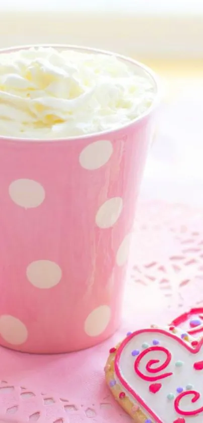 Pink polka dot cup with cream and heart cookie on pink background.