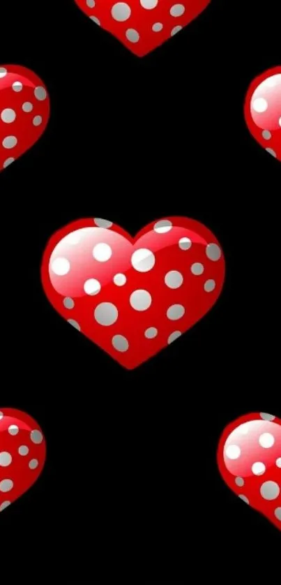 Red polka dot hearts on black wallpaper.