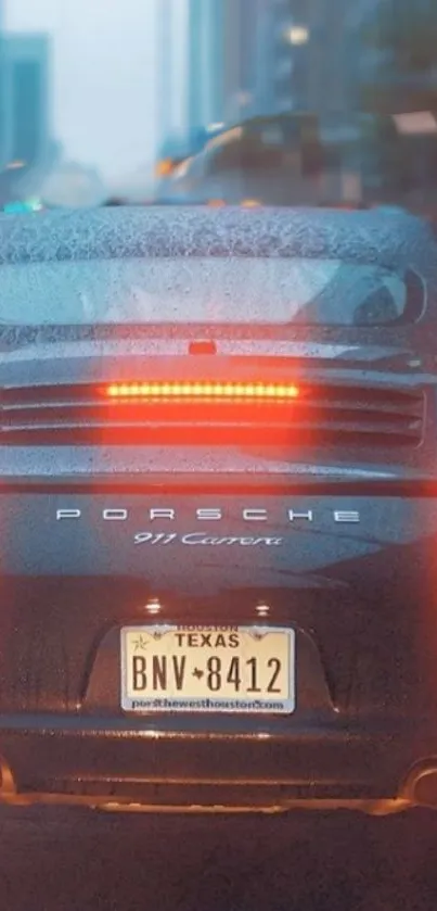 Porsche 911 Carrera driving in a rainy cityscape.