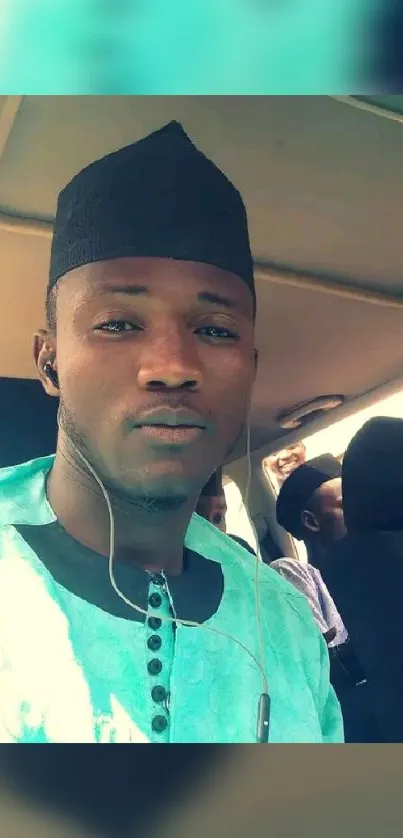 Man in a light aqua shirt with a calm expression sitting in a vehicle.