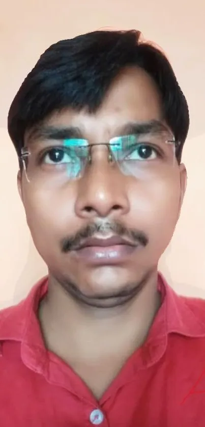 Portrait of a person wearing glasses and a red shirt on a neutral background.