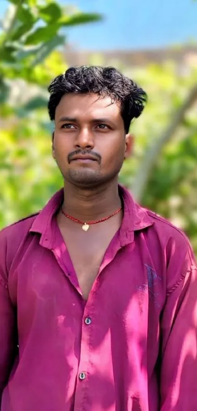 Man in vibrant shirt amidst greenery, outdoors.