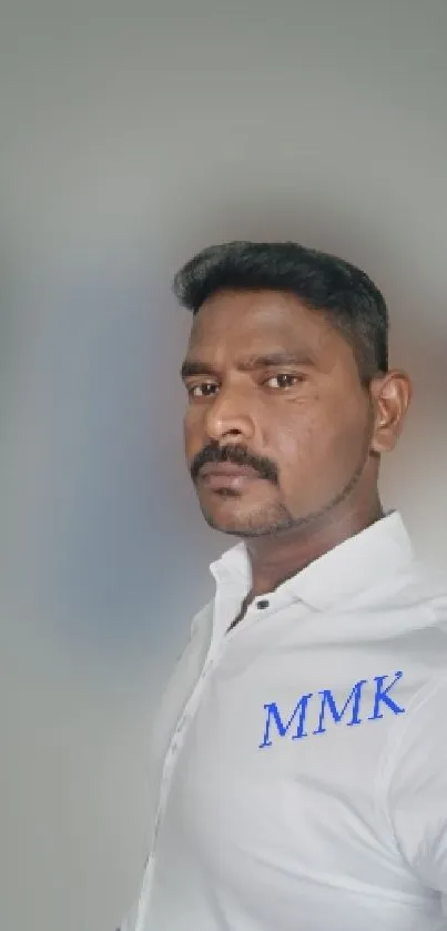 Portrait of a man in a white shirt with a blurred gray background.