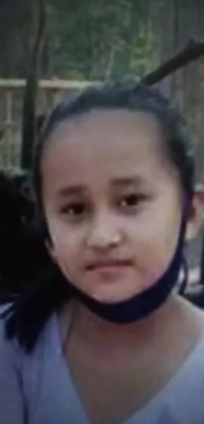 A portrait of a young girl with a calm expression outdoors.