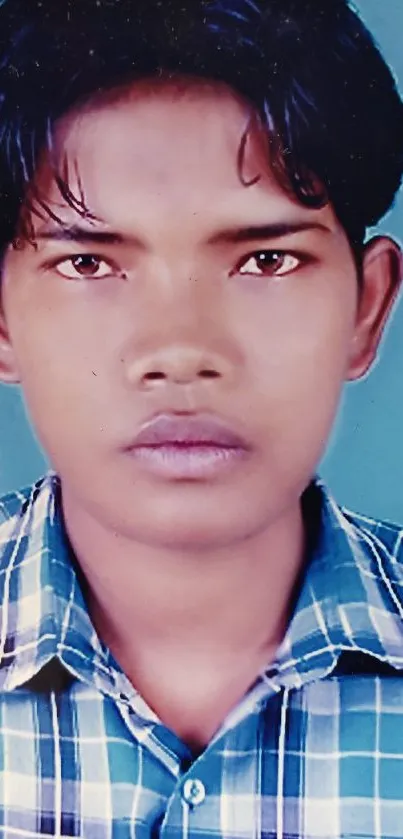 Young person with plaid shirt on blue background.