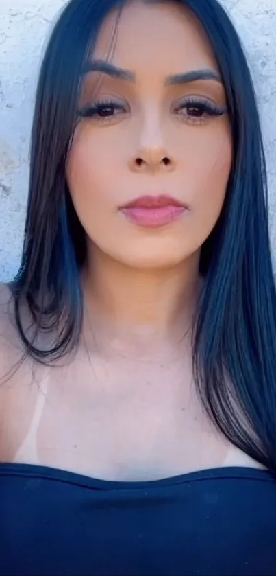 Portrait of woman with long dark hair against light background.