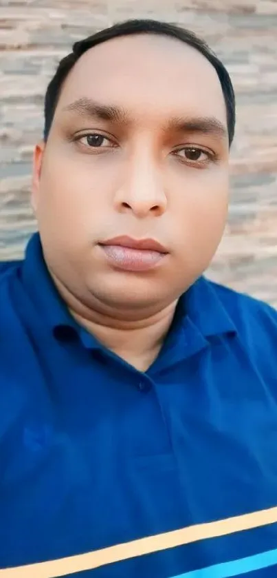 Person in blue shirt against a textured wall.