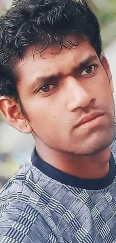 Portrait of a young man with a patterned shirt and thoughtful expression.