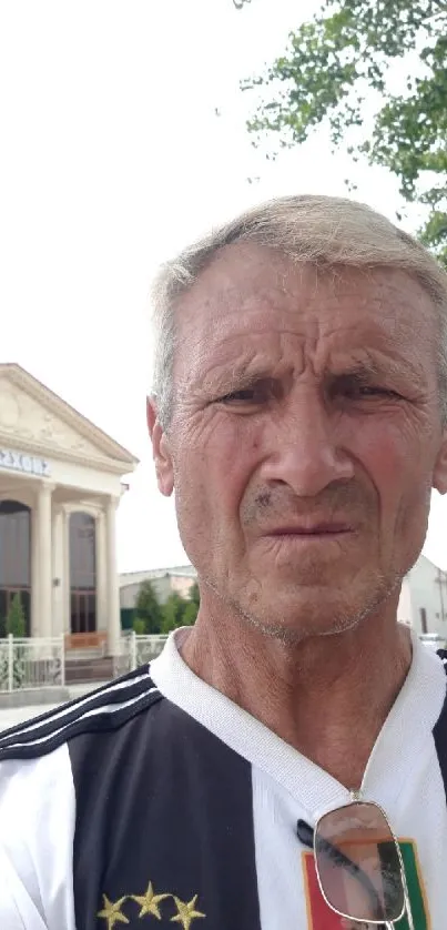 Mature man in casual attire with building background.