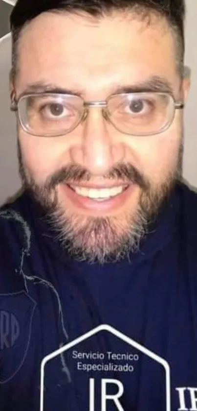 Smiling man with glasses and beard, wearing a navy shirt.