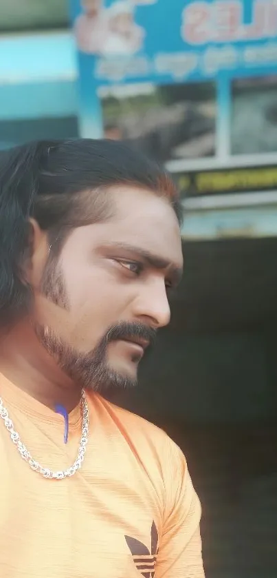 Man in orange shirt with thoughtful expression.