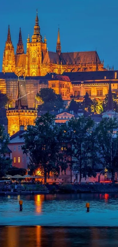 Prague Castle illuminated at night with river reflections.