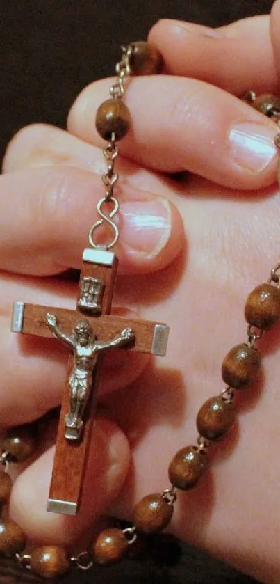 Hands holding a rosary with wooden beads and crucifix, symbolizing prayer.