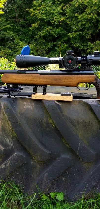 Rifle with scope on forest tire backdrop