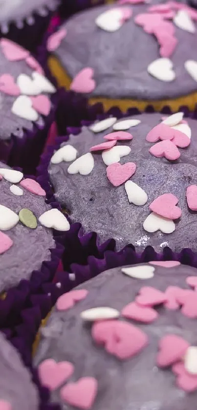 Purple cupcakes with pink and white heart sprinkles in a box.