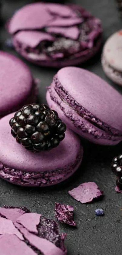 Purple macarons with blackberries on a dark surface.