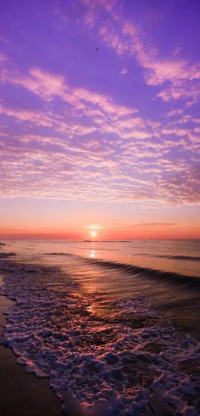 Purple sunset over a serene beach with waves and clouds.